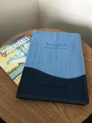 a blue book sitting on top of a wooden table at SunnyVale Valley View Cottage in Gorran Haven