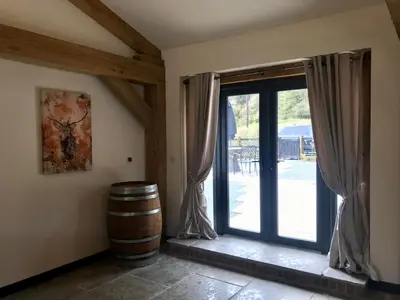 a room with a barrel and a glass door at Trelaske Mill Cider Barn-with Hot Tub, Fire Pit BBQ in Lewannick