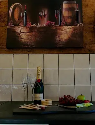 a bottle of wine sitting on a counter with wine glasses at Trelaske Mill Cider Barn-with Hot Tub, Fire Pit BBQ in Lewannick