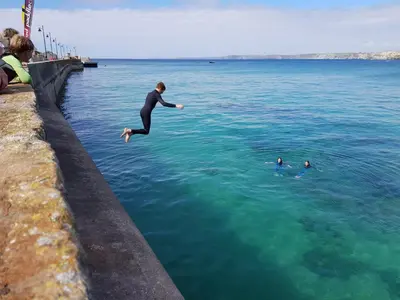 a man jumping into the water in the ocean at Hidden Gem near the beach with pool table in Newquay