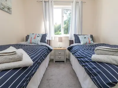 two twin beds in a room with a window at Owls Roost in Falmouth