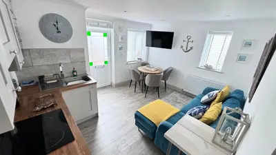 a living room with a blue couch and a kitchen at ABOVE PORTHMINSTER BEACH - 