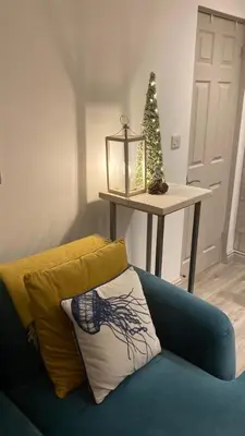 a blue couch with a pillow and a christmas tree at ABOVE PORTHMINSTER BEACH - 
