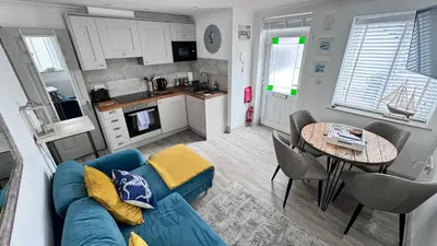 a living room with a blue couch and a table at ABOVE PORTHMINSTER BEACH - 