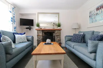 a living room with blue couches and a fireplace at Idyllic Cottage near Padstow in Little Petherick