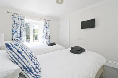 a bedroom with two beds and a tv on the wall at Idyllic Cottage near Padstow in Little Petherick