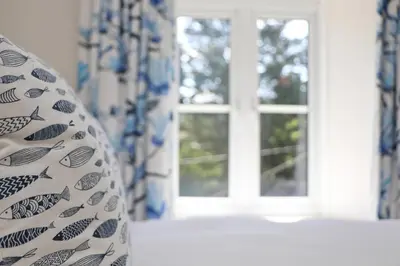 a window in a room with blue and white curtains at Idyllic Cottage near Padstow in Little Petherick