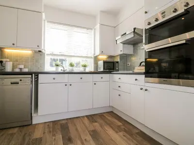 a kitchen with white cabinets and stainless steel appliances at Badgers Way in Tintagel