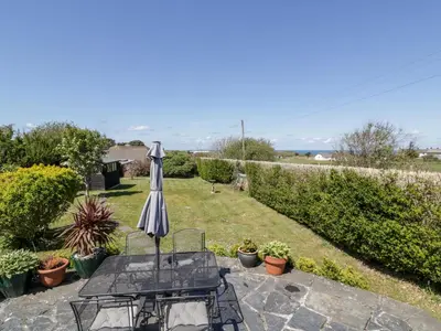 a patio with an umbrella and a table and chairs at Badgers Way in Tintagel