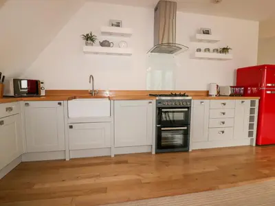 a kitchen with white cabinets and a red refrigerator at Crabs and Lobsters in Newquay