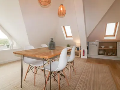 a dining room with a wooden table and white chairs at Crabs and Lobsters in Newquay