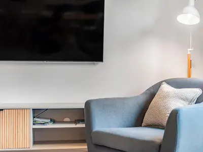 a living room with a blue chair and a flat screen tv at Chi Gwynn in Newquay