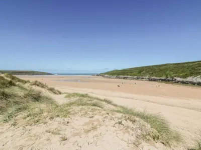 a beach with people walking on the sand at Chi Gwynn in Newquay