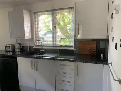 a kitchen with white cabinets and a sink and a window at 44 Trevithick view in Saint Erth