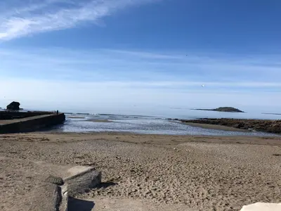 a beach with rocks and the ocean on a cloudy day at 2 Bed Villa Sleeps 4 - Wifi Garden Sea Views in Looe