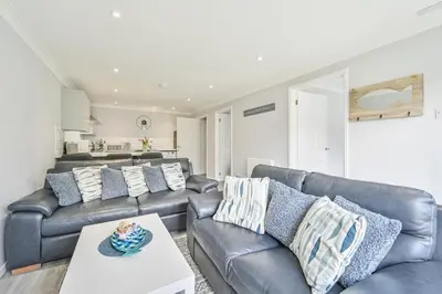 a living room with couches and a table at 2 Bed Villa Sleeps 4 - Wifi Garden Sea Views in Looe