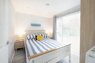 a bedroom with a bed with a yellow pillow on it at 2 Bed Villa Sleeps 4 - Wifi Garden Sea Views in Looe