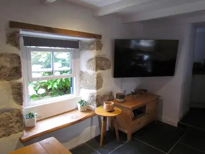 a room with a window and a television on the wall at Trenwith Bridge Cottage in St Ives