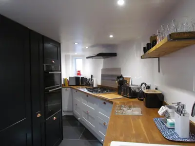 a kitchen with white cabinets and a black refrigerator at Trenwith Bridge Cottage in St Ives