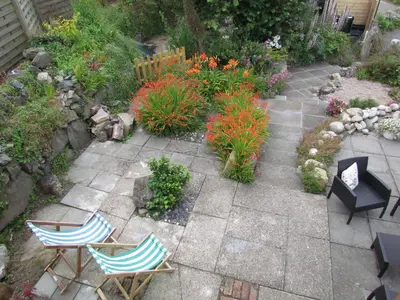 a patio with two chairs and a table and flowers at Trenwith Bridge Cottage in St Ives