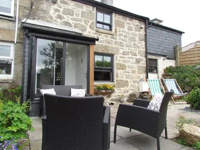 a patio with wicker chairs and a house at Trenwith Bridge Cottage in St Ives