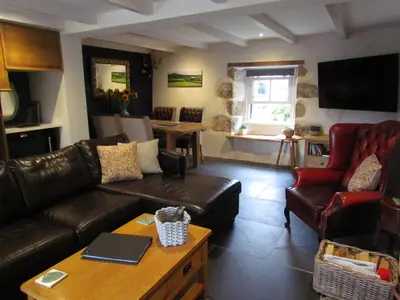 a living room with a leather couch and chairs at Trenwith Bridge Cottage in St Ives