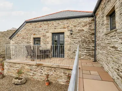 a patio with a table and chairs on a brick building at The Hayloft in Bodmin