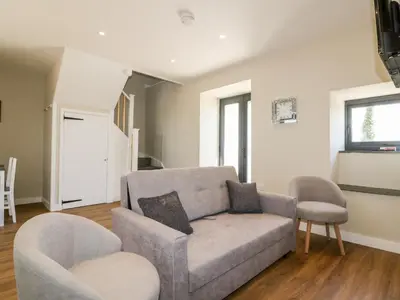 a living room with a couch and two chairs at The Hayloft in Bodmin