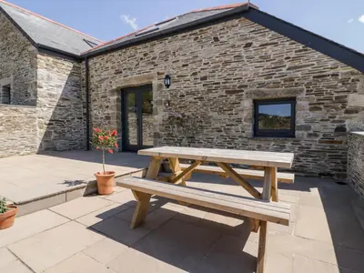 a wooden picnic table in front of a brick building at The Hayloft in Bodmin