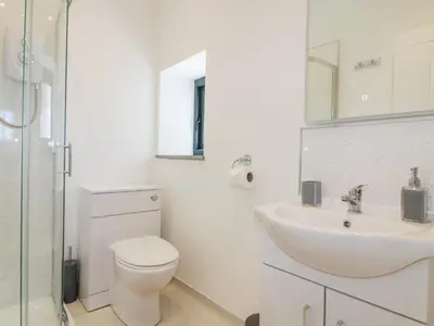a white bathroom with a toilet and a sink at The Hayloft in Bodmin