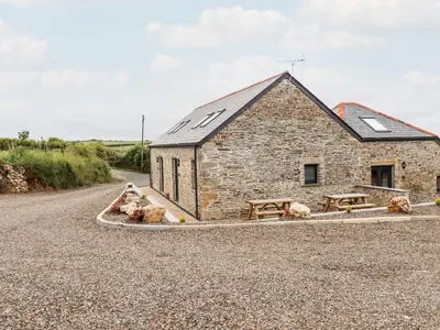 a stone barn with picnic tables in front of a road at The Granary in Bodmin