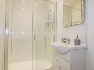 a white bathroom with a sink and a shower at The Granary in Bodmin