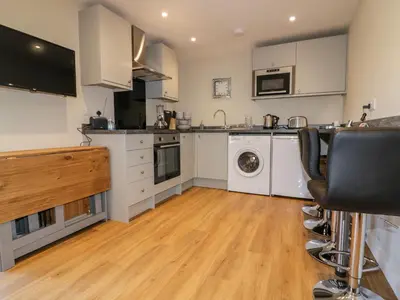a kitchen with white cabinets and a washer and dryer at The Granary in Bodmin