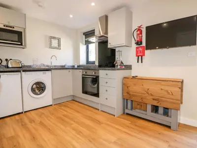 a kitchen with white cabinets and a washer and dryer at The Cornstore in Bodmin