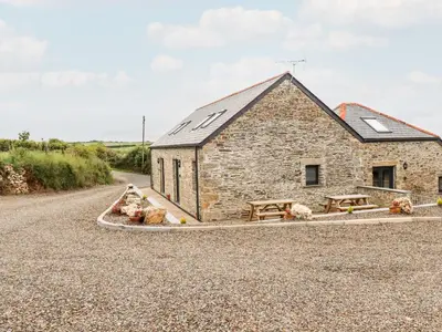 a stone barn with picnic tables in front of a road at The Cornstore in Bodmin