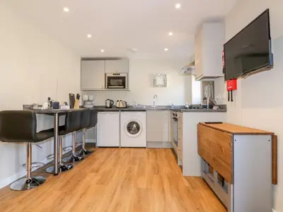 a kitchen with white cabinets and a sink and a dishwasher at The Cornstore in Bodmin