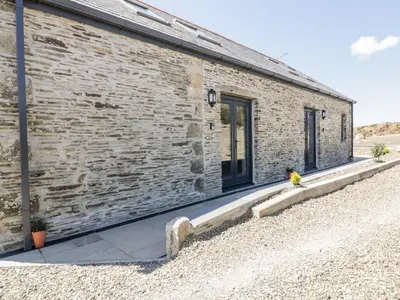 a brick building with a yellow bird sitting on a curb at The Cornstore in Bodmin