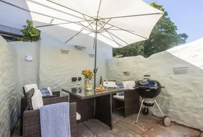 a grill and an umbrella on a patio at Oriel Cottage in St. Agnes