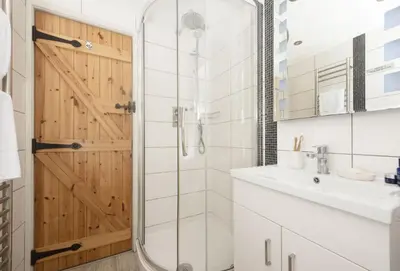 a bathroom with a shower and a glass door at Oriel Cottage in St. Agnes