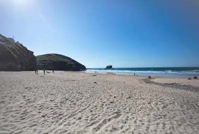 a beach with people walking on the sand and the ocean at Oriel Cottage in St. Agnes