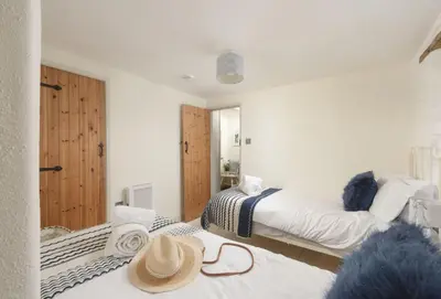 a bedroom with two beds with hats on top of them at Oriel Cottage in St. Agnes