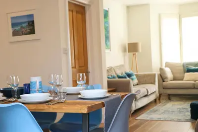 a dining room with a table and chairs and a living room at Padstow townhouse, close to harbour in Padstow