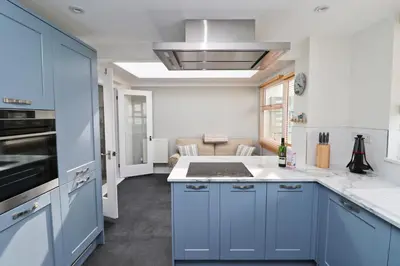 a kitchen with blue cabinets and a living room at Padstow townhouse, close to harbour in Padstow