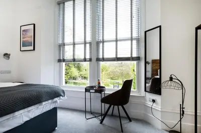 a bedroom with a bed and a chair and windows at Park View in Falmouth