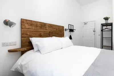 a bedroom with a white bed with a wooden headboard at Park View in Falmouth