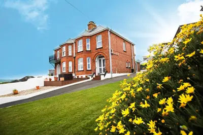 a brick building with yellow flowers in front of it at No 10 Treverbyn Road B & B in Padstow