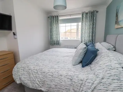 a bedroom with a bed with blue pillows and a window at Beach Cottage in Redruth
