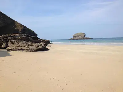 a sandy beach with a rock in the ocean at Beach Cottage in Redruth