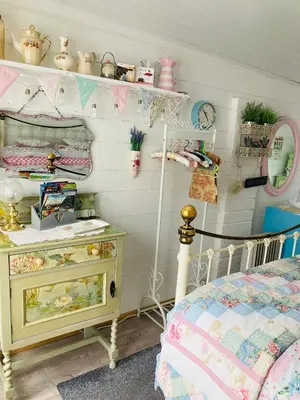 a bedroom with a bed and a dresser and shelves at Shabby Shack near Charlestown & The Eden Project in St Austell
