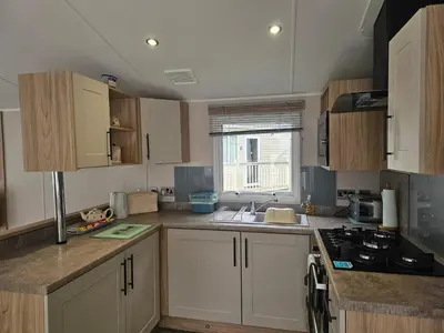 a kitchen with white cabinets and a sink and a stove at Mawgan Pads Trevella Crantock in Crantock